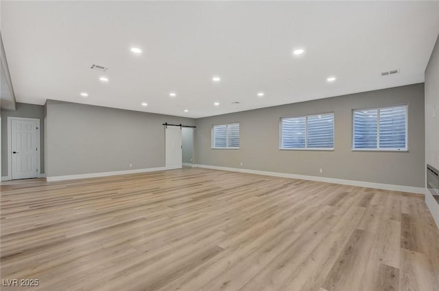 empty room with light hardwood / wood-style floors and a barn door