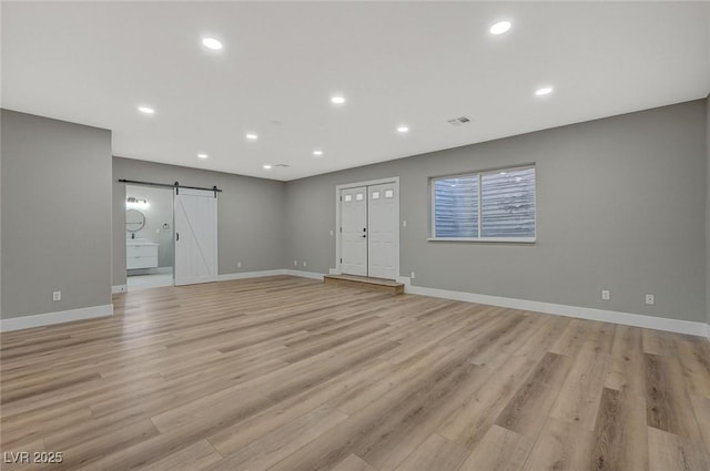 unfurnished living room with light hardwood / wood-style flooring and a barn door