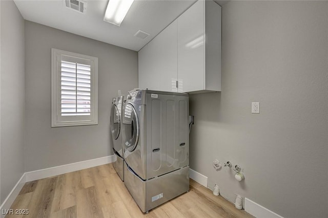 laundry area with light hardwood / wood-style floors, cabinets, and separate washer and dryer