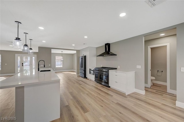 kitchen featuring a large island, stainless steel appliances, pendant lighting, wall chimney exhaust hood, and sink