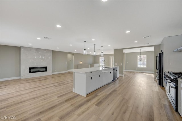 kitchen featuring white cabinetry, a large island, decorative light fixtures, range with two ovens, and a fireplace