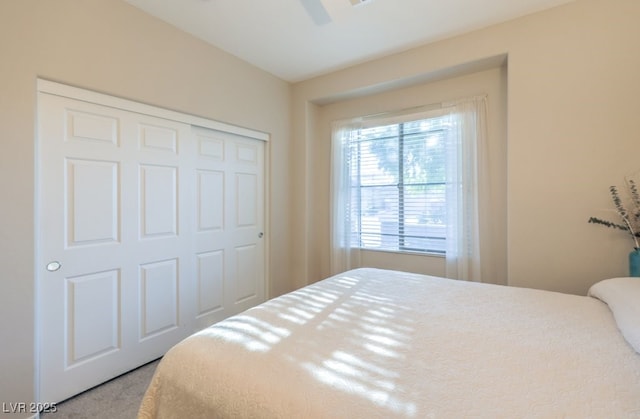 carpeted bedroom with ceiling fan and a closet