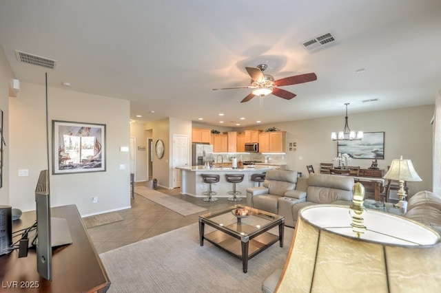 tiled living room featuring ceiling fan with notable chandelier