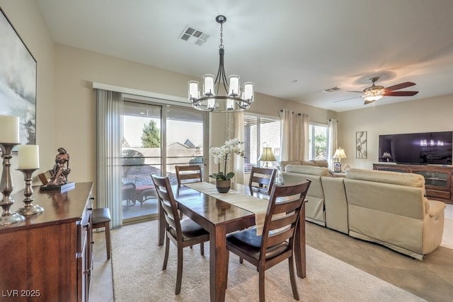 tiled dining space with ceiling fan with notable chandelier