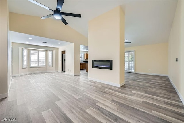 unfurnished living room featuring ceiling fan, light wood-type flooring, and high vaulted ceiling