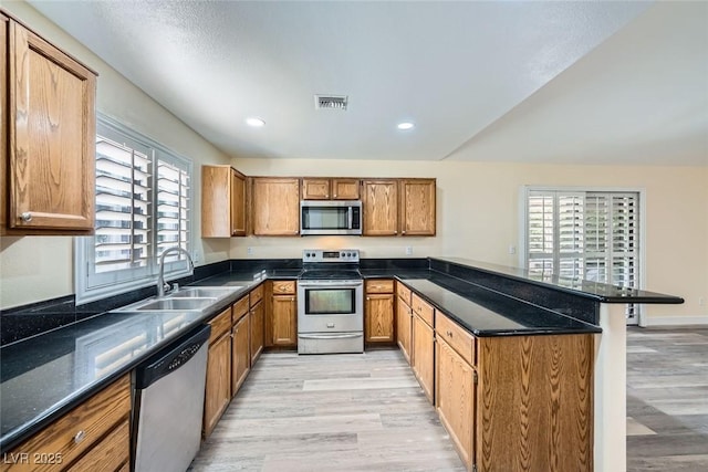 kitchen with light hardwood / wood-style floors, kitchen peninsula, a breakfast bar area, appliances with stainless steel finishes, and sink