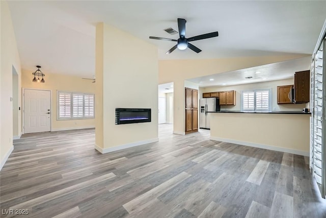 unfurnished living room with ceiling fan, light wood-type flooring, heating unit, and high vaulted ceiling