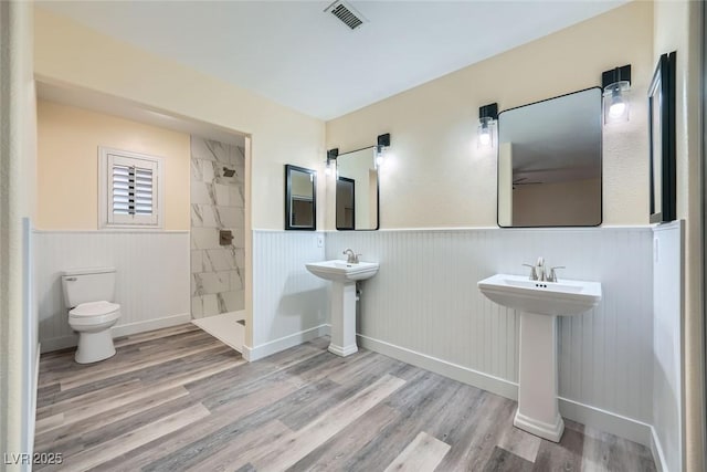 bathroom featuring toilet, sink, tiled shower, and hardwood / wood-style flooring