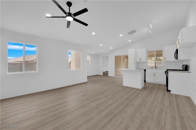 unfurnished living room featuring ceiling fan, lofted ceiling, and light hardwood / wood-style flooring