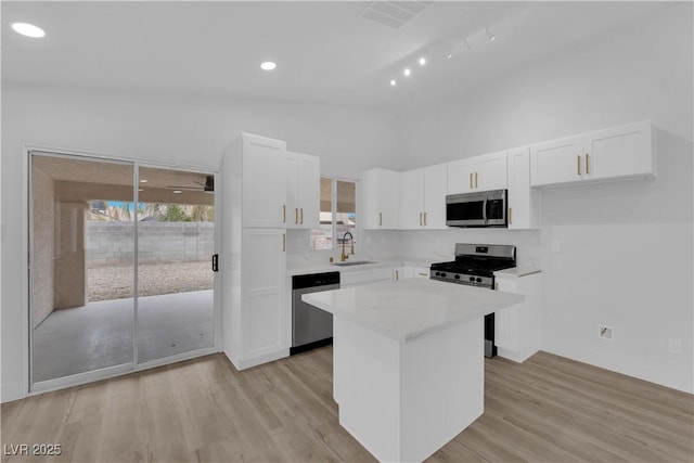 kitchen with white cabinets, appliances with stainless steel finishes, sink, and a center island