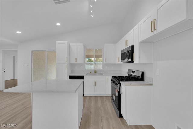 kitchen with white cabinets, a center island, stainless steel appliances, sink, and light stone counters