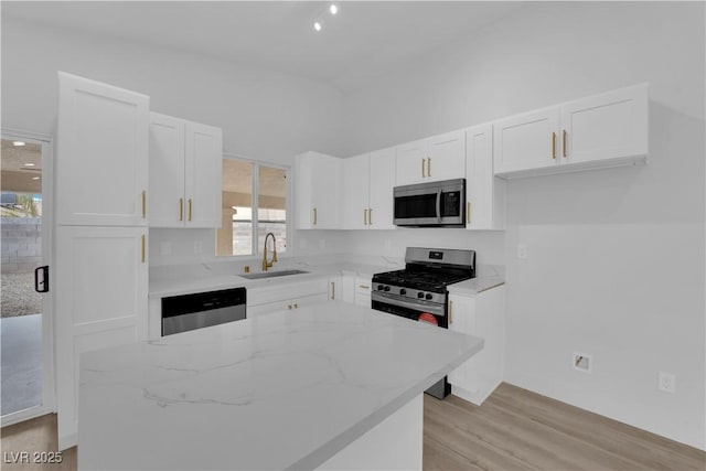 kitchen featuring a wealth of natural light, white cabinetry, stainless steel appliances, sink, and light stone counters