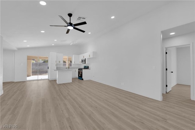 unfurnished living room with ceiling fan, lofted ceiling, light hardwood / wood-style floors, and sink