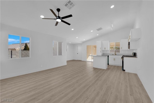 unfurnished living room featuring light wood-type flooring, ceiling fan, vaulted ceiling, and sink