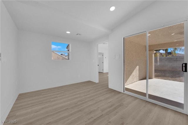 spare room featuring lofted ceiling and light wood-type flooring