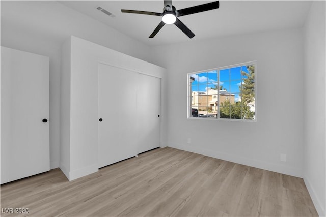 unfurnished bedroom featuring ceiling fan, light hardwood / wood-style floors, and a closet