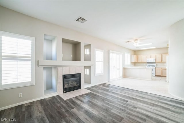 unfurnished living room featuring ceiling fan, a fireplace, and light hardwood / wood-style flooring