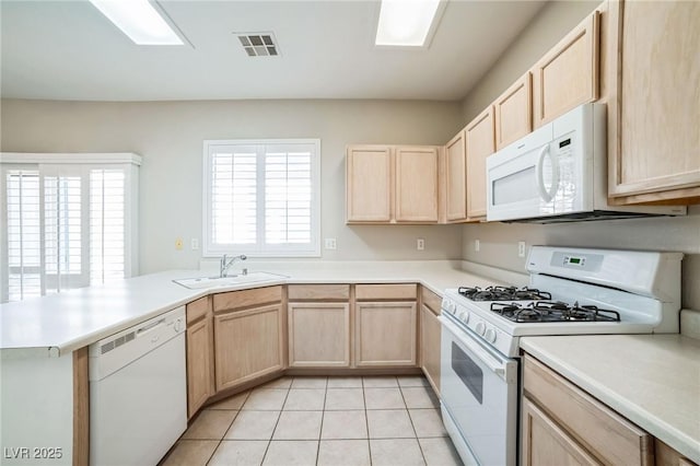 kitchen with light tile patterned floors, kitchen peninsula, white appliances, light brown cabinetry, and sink