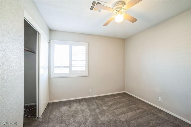 unfurnished bedroom featuring ceiling fan, a closet, and dark colored carpet