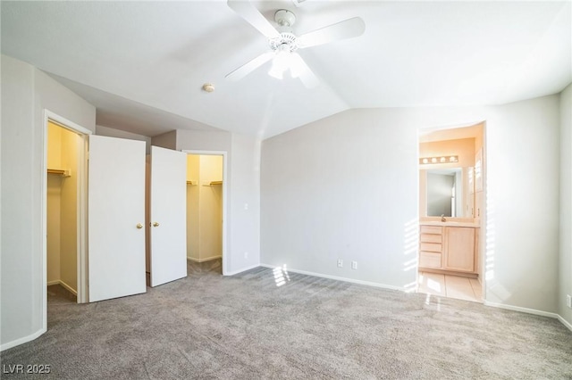 unfurnished bedroom featuring ceiling fan, a walk in closet, carpet, and connected bathroom