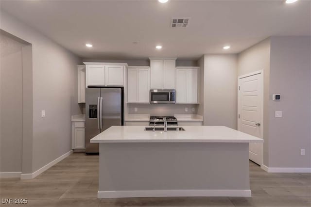 kitchen featuring sink, white cabinetry, appliances with stainless steel finishes, and a kitchen island with sink