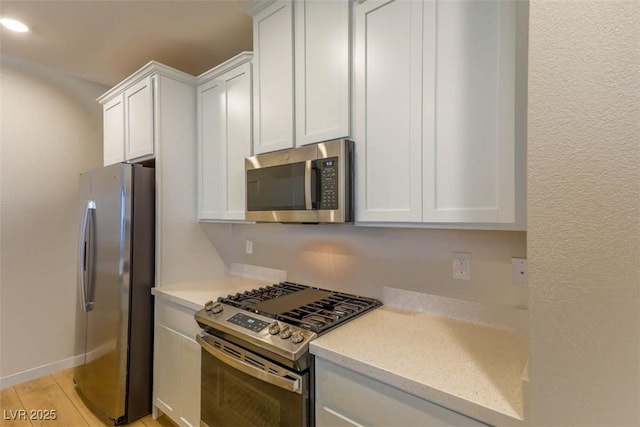 kitchen with light wood-type flooring, appliances with stainless steel finishes, and white cabinets