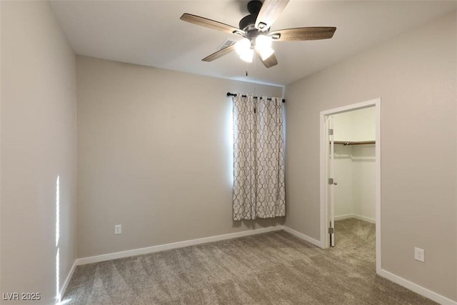 unfurnished bedroom with ceiling fan, a walk in closet, a closet, and light carpet