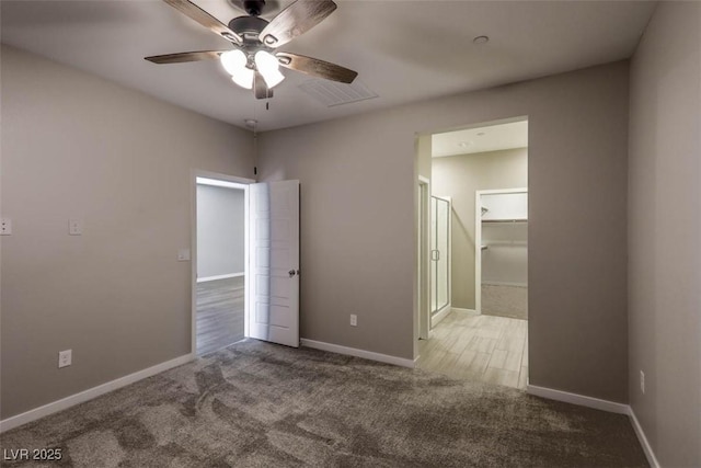 unfurnished bedroom with ceiling fan, light colored carpet, a closet, and a walk in closet