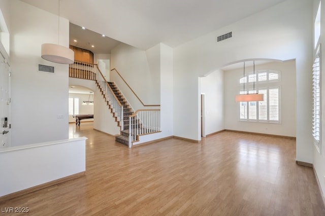 interior space with light wood-style floors, visible vents, a high ceiling, and arched walkways