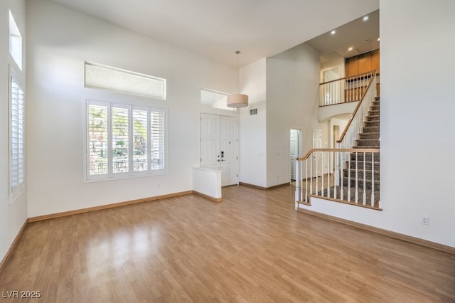 foyer with stairs, baseboards, a high ceiling, and wood finished floors