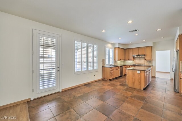 kitchen featuring a sink, visible vents, a center island, decorative backsplash, and dishwasher