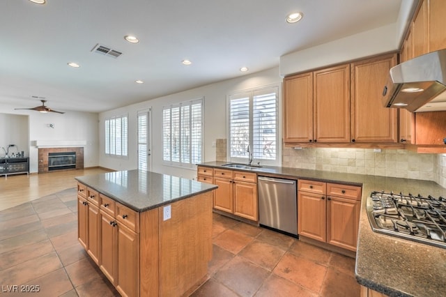 kitchen with visible vents, appliances with stainless steel finishes, open floor plan, a kitchen island, and ventilation hood