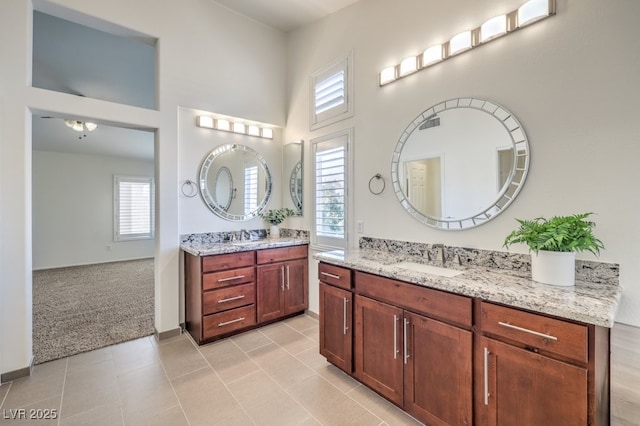 bathroom with a towering ceiling, two vanities, a sink, and tile patterned floors