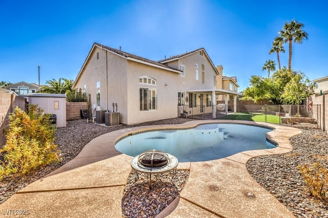 view of swimming pool with central AC unit, a storage unit, a patio area, and an outdoor fire pit