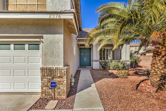 view of exterior entry with an attached garage and stucco siding