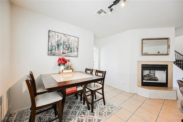 dining area featuring track lighting, light tile patterned floors, and a fireplace