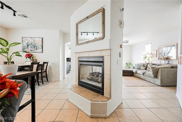 living room with light tile patterned floors, a tile fireplace, and rail lighting