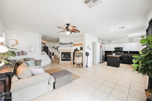 living room with ceiling fan, light tile patterned flooring, and a tile fireplace