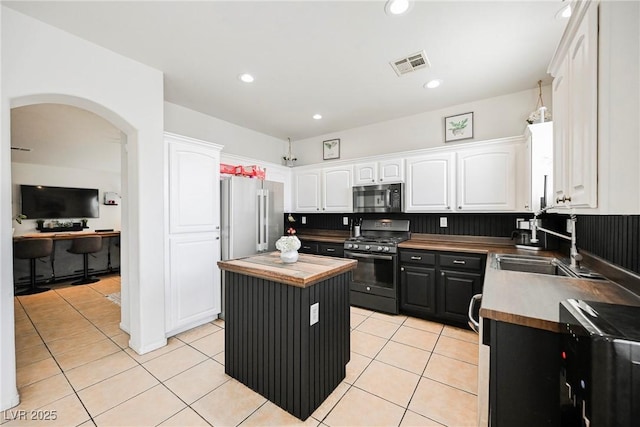 kitchen with a center island, white cabinetry, stainless steel appliances, sink, and light tile patterned floors