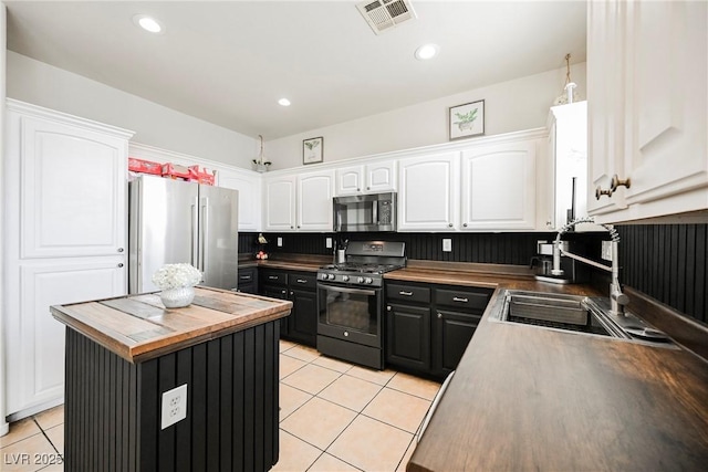 kitchen featuring light tile patterned floors, white cabinetry, appliances with stainless steel finishes, sink, and a center island