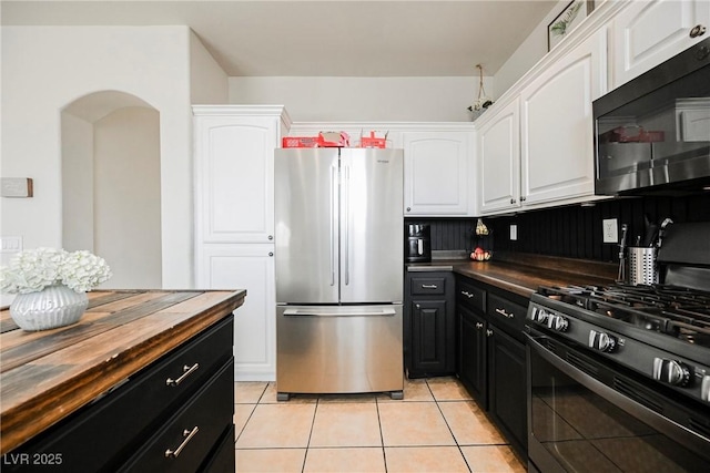 kitchen with light tile patterned floors, white cabinetry, range with gas stovetop, and stainless steel refrigerator