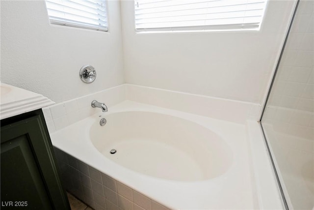 bathroom with vanity and a relaxing tiled tub