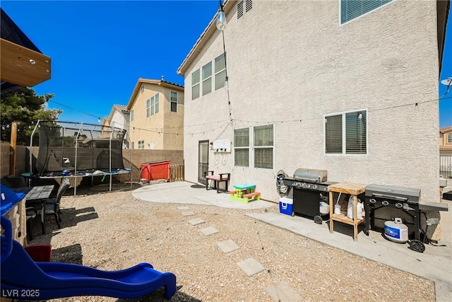 rear view of property with a playground, a trampoline, and a patio