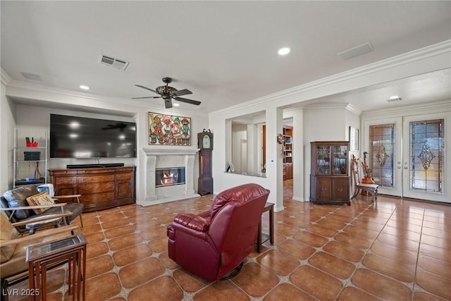 tiled living room featuring ceiling fan, crown molding, and french doors