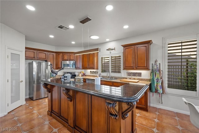 kitchen featuring decorative light fixtures, plenty of natural light, appliances with stainless steel finishes, and a kitchen island