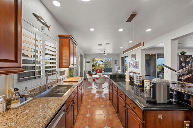 kitchen with ceiling fan, dark stone countertops, hanging light fixtures, and sink