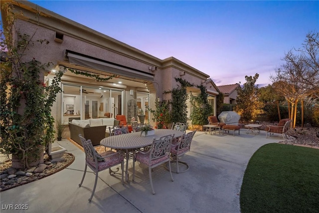 patio terrace at dusk with an outdoor living space and area for grilling