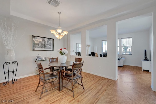 dining space featuring light tile patterned floors, a tray ceiling, and a chandelier