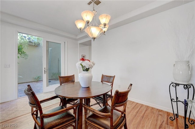 dining room with light hardwood / wood-style floors, a tray ceiling, and an inviting chandelier