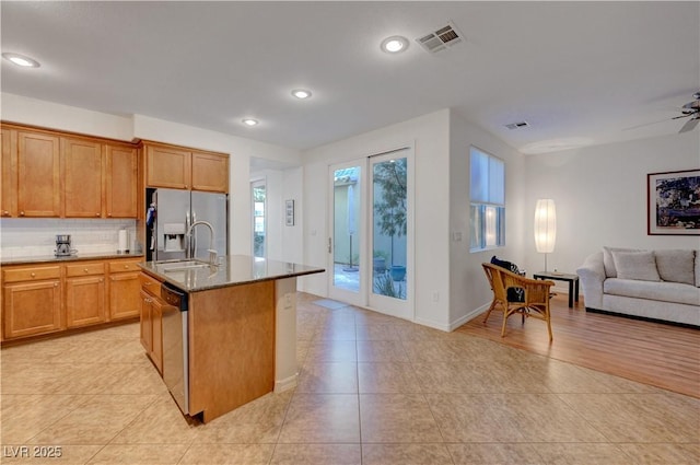 kitchen featuring ceiling fan, backsplash, sink, appliances with stainless steel finishes, and an island with sink